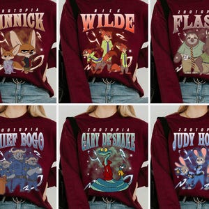 May include: Maroon long-sleeved tops featuring characters from the film "Zootopia." Each top displays a different character's name and image: Finnick, Nick Wilde, Flash, Chief Bogo, Gary De'Snake, and Judy Hopps. The tops are paired with blue jeans.