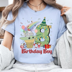 May include: Light blue t-shirt with a green number eight, a rainbow, and a cartoon character holding a cone of ice cream. The text "8th Birthday Boy" is printed on the shirt.