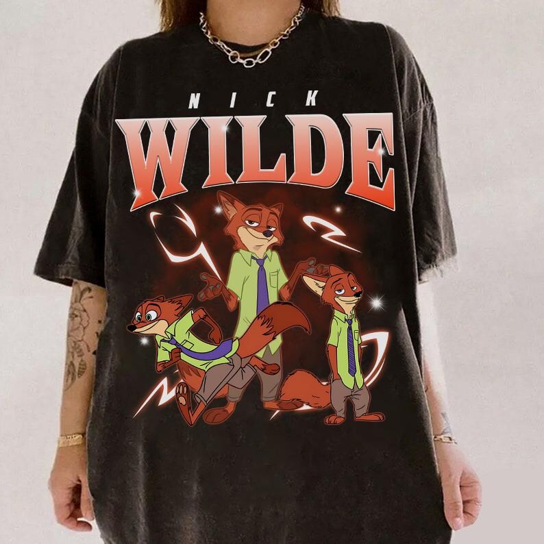 May include: Black t-shirt with a graphic of Nick Wilde from Zootropolis. The design includes the name "NICK WILDE" in large, red and white letters above an illustration of the character in various poses, wearing a green shirt and tie.