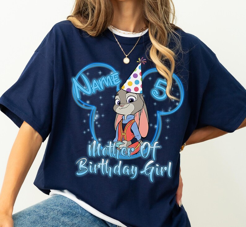 Puede incluir: Camiseta azul marino con una imagen de dibujos animados de Judy Hopps de Zootopia con un gorro de fiesta. La camiseta tiene el texto "Name 5 Mother of Birthday Girl" en fuente azul claro, con un contorno en forma de Mickey Mouse.