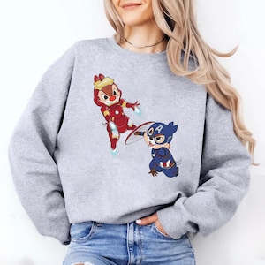 May include: A gray sweatshirt with a cartoon image of two chipmunks dressed as superheroes. One chipmunk is dressed as Iron Man and the other is dressed as Captain America.