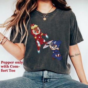 May include: A dark grey t-shirt with a graphic print of two cartoon chipmunks dressed as Iron Man and Captain America. The text "More Ocean" is visible on the right sleeve.