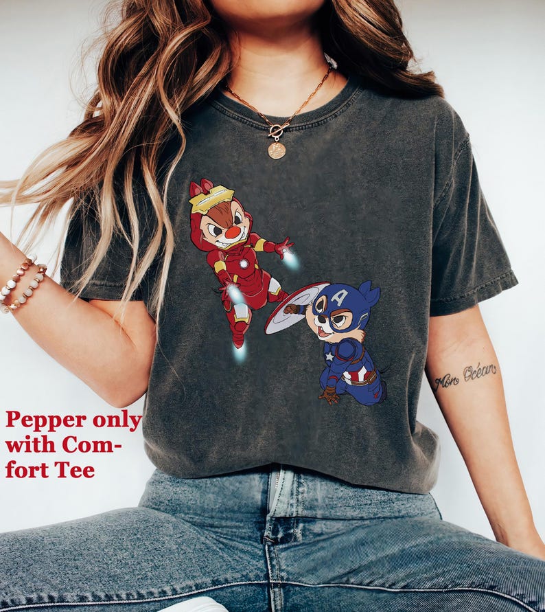 May include: A dark grey t-shirt with a graphic print of two cartoon chipmunks dressed as Iron Man and Captain America. The text "More Ocean" is visible on the right sleeve.