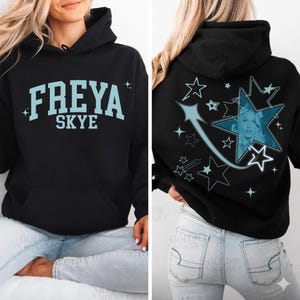 May include: Black hooded sweatshirt with the text "FREYA SKYE" in light blue on the front. The back features a star design with a photo and shooting star graphic in light blue. The sweatshirt has a front pocket.
