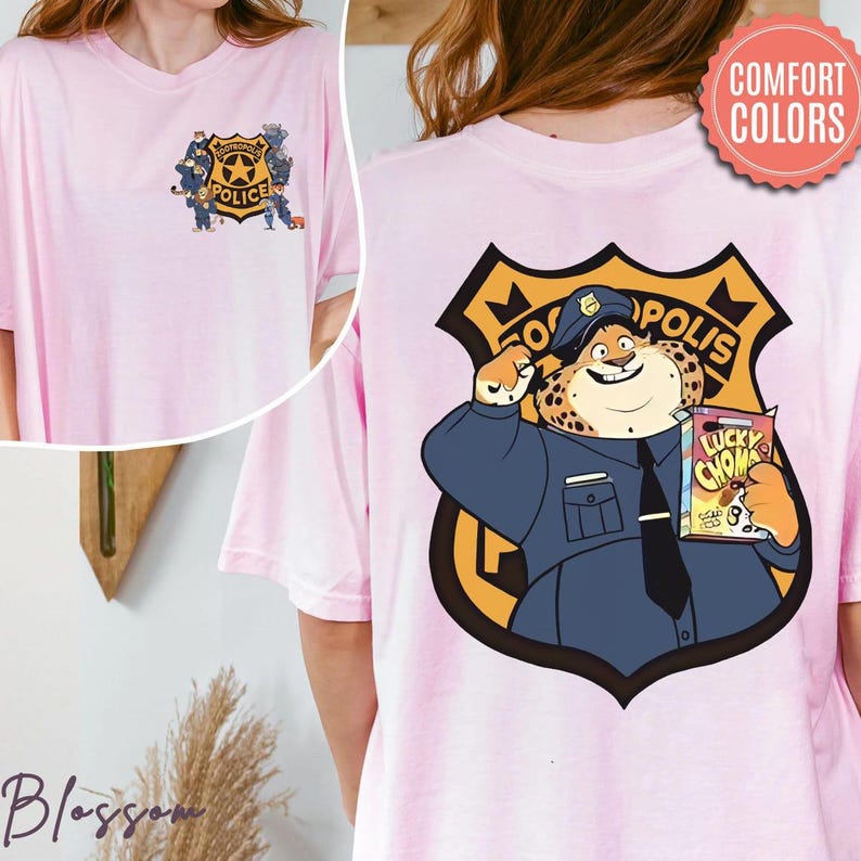 Puede incluir: Camiseta rosa claro con un dise&ntilde;o de insignia de polic&iacute;a de dibujos animados. La parte trasera muestra a un oficial de polic&iacute;a guepardo sosteniendo un bocadillo, mientras que la parte delantera tiene una insignia de polic&iacute;a con el texto "POLICE".