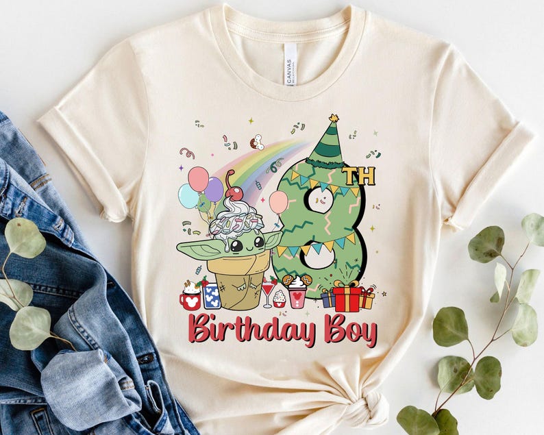 May include: A beige t-shirt with a green and white cartoon character holding a green ice cream cone. The character is standing next to a green number eight with a party hat. The text "Birthday Boy" is printed in red below the characters.