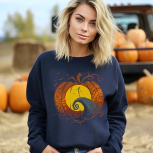 Pode incluir: Uma camisola azul-marinho com um gr&aacute;fico de Jack Skellington em p&eacute; sobre uma ab&oacute;bora com uma lua amarela no fundo. O gr&aacute;fico &eacute; de estilo vintage com cores laranja, amarelo e castanho.