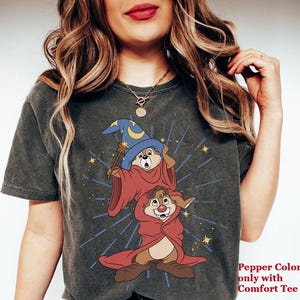 May include: Dark grey t-shirt with a cartoon illustration of two chipmunks dressed as wizards. The top chipmunk wears a blue wizard hat and holds a wand. The bottom chipmunk is in a red robe. Text on the bottom right reads "Pepper Color only with Comfort Tee."