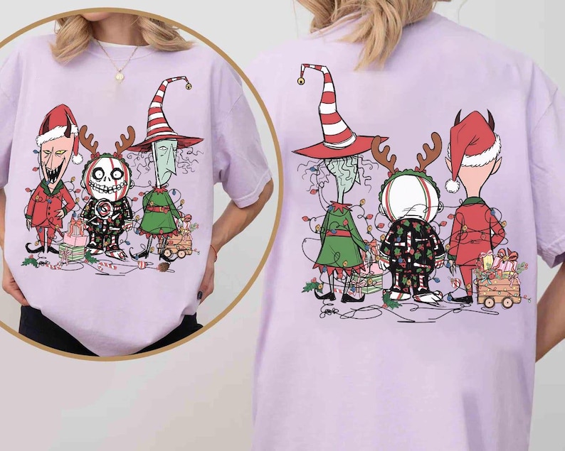 K&ouml;nnte beinhalten: Helllila T-Shirt mit einer Cartoon-Illustration von drei festlichen Charakteren. Sie sind mit Weihnachtsbeleuchtung geschm&uuml;ckt und stehen in der N&auml;he eines kleinen Wagens voller Geschenke. Das Design ist auf der Vorder- und R&uuml;ckseite des T-Shirts aufgedruckt.