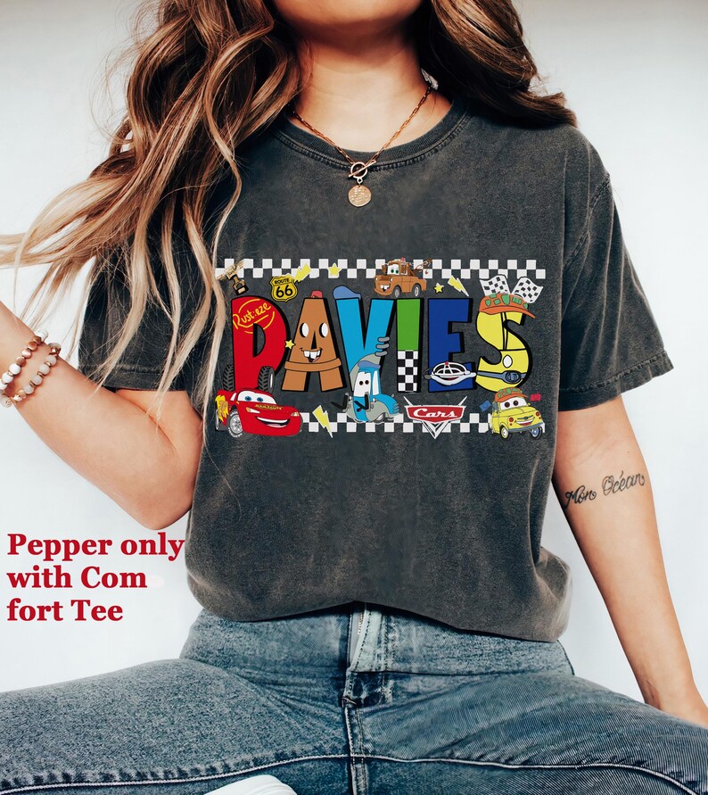 May include: Dark gray t-shirt featuring the name "DAVIES" in colorful, cartoon-style lettering with car graphics. The shirt has a distressed look and includes the text "Pepper only with Comfort Tee".