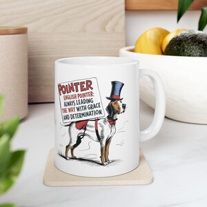 May include: White ceramic mug with a graphic of an English Pointer dog wearing a top hat and holding a sign that reads "POINTER ENGLISH POINTER: ALWAYS LEADING THE WAY WITH GRACE AND DETERMINATION."
