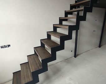 May include: A modern staircase with black metal railings and wooden steps. The staircase is angled and leads up to a higher level.