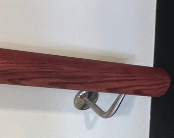May include: A dark red wooden handrail with silver metal brackets. The handrail is mounted to a white wall.