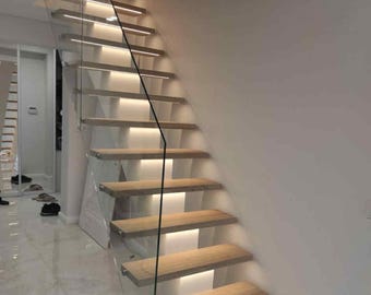 May include: A modern staircase with wooden steps and glass railings. Each step is illuminated with a warm, soft light, creating a visually appealing and contemporary design. The staircase leads upwards, suggesting a transition to another level.