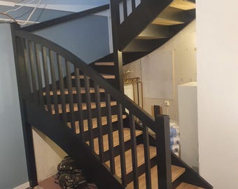 May include: Black wooden staircase with a curved handrail and wooden steps. The staircase is in a home with a light blue wall and a white ceiling.