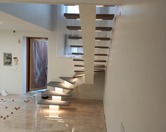 May include: A modern staircase with wooden steps and a white railing. The staircase is lit by recessed lighting and is located in a room with a white ceiling and walls.