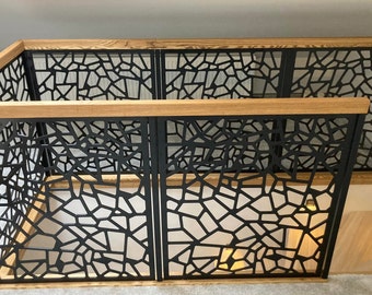 May include: Black metal railing with a geometric pattern and a wooden top rail. The railing is installed on a staircase.