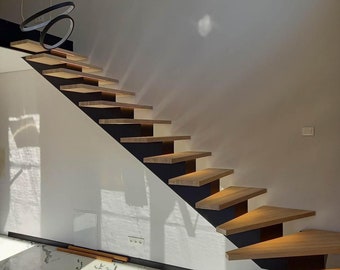 May include: A modern staircase with wooden steps and black metal railings. The staircase is lit by recessed lighting and is located in a room with white walls and a marble floor.