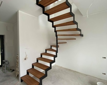 May include: A modern staircase with wooden steps and black metal railings. The staircase is in a room with white walls and a concrete floor.