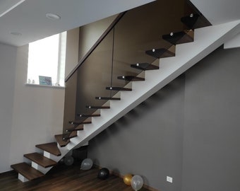 May include: A modern staircase with dark wood steps and a glass railing. The steps are supported by white risers, and the wall is painted a neutral gray. The staircase leads upwards, with a window visible in the background.