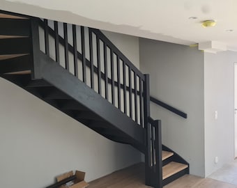 May include: Black wooden staircase with a curved design and black metal railings. The staircase is in a modern home with white walls.
