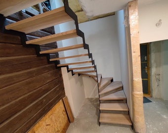 May include: A modern wooden staircase with black metal railings. The stairs are made of light wood and have a curved design. The stairs are in a room with white walls and a wooden floor.