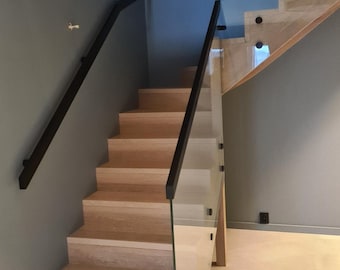 May include: A wooden staircase with a glass and black metal railing. The stairs are made of light wood and have a natural finish. The railing is made of black metal and has a modern design.