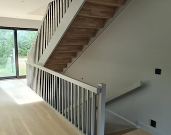 May include: A modern staircase with wooden steps and a white painted railing. The staircase is in a home with light gray walls and wooden floors.