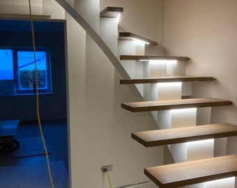 May include: A modern staircase with white risers and wooden treads. Each step has a built-in LED light strip that illuminates the steps. The staircase is curved and has a white wall behind it.