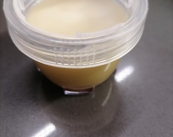 May include: A clear plastic container with a lid filled with a light yellow liquid.