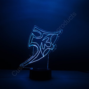 May include: A blue LED night light shaped like a stylized abstract design. The light is on a black base.
