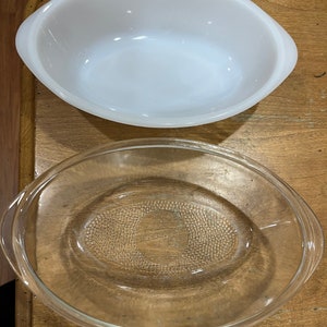 May include: Two oval baking dishes, one white and one clear glass. The glass dish has a textured bottom with the word "Fire King" embossed on it.