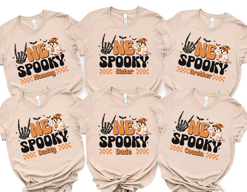 six beige t-shirts with Halloween-themed designs, including a skeleton hand, bats, and the text "NE SPOKEY" and "Sister" printed on them.