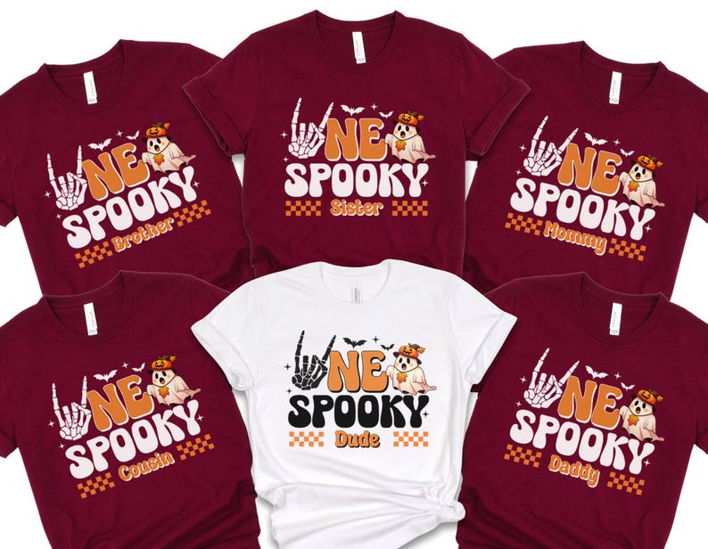 a collection of seven burgundy t-shirts with the same Halloween-themed design, including a skeleton hand and the text "NE SPOKEY SISTER" and "NE SPOKEY Dude".