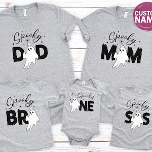 a collection of gray t-shirts with the text "Spooky" printed on them, along with various ghost-like designs. The t-shirts appear to be family-sized, suggesting they are intended for a group of people, possibly for a Halloween or themed event.