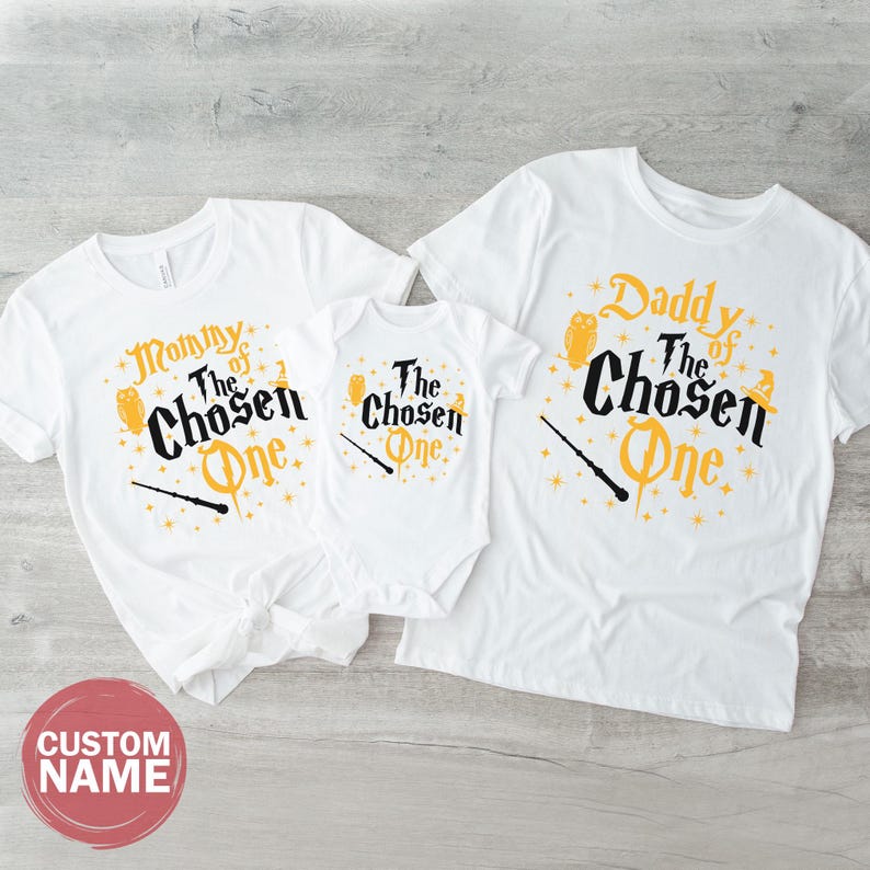 three white t-shirts with the same design, laid out on a wooden surface.