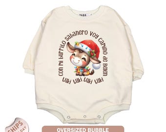 May include: Cream-colored, long-sleeve baby bodysuit. The front features a cartoon donkey wearing a Santa hat and Christmas lights, with text in a circular pattern. The bottom of the bodysuit has snap closures. The text on the bottom reads "Oversized Bubble Long-Sleeve Bodysuit."