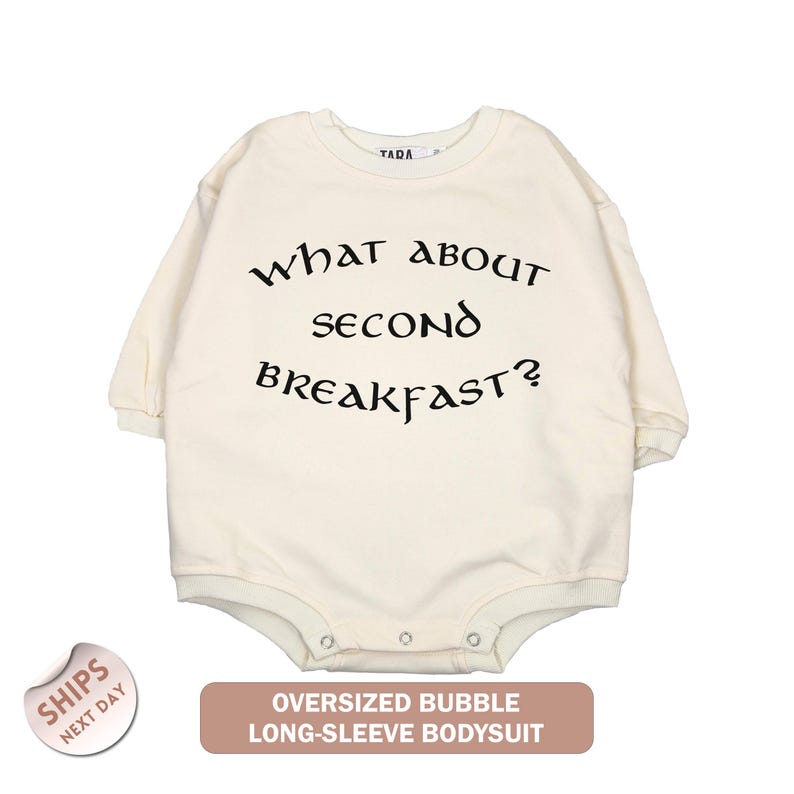 a white long-sleeved bodysuit with the text "What about second breakfast?" printed on it.