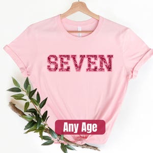 a pink t - shirt with the word seven printed on it