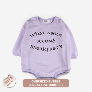 A long-sleeved purple bodysuit with the text "What about second breakfast?" printed on it.