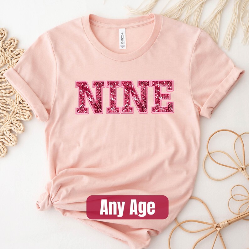 a pink shirt with the word nine on it