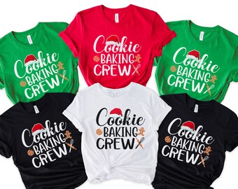 May include: A collection of crew neck t-shirts in various colors: green, red, black, and white. Each shirt features the text "Cookie Baking Crew" in white, with a Santa hat, gingerbread man, cookie, and whisk graphic.
