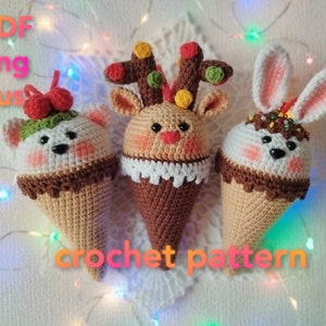 Peut inclure: Trois décorations en forme de cornet de glace en crochet, chacune avec un visage d'animal différent. Les décorations sont un ours blanc avec des baies rouges, un renne avec des bois bruns et un lapin blanc avec des oreilles brunes. Les décorations sont toutes brunes et blanches et ont un dessus brun ressemblant à du chocolat.