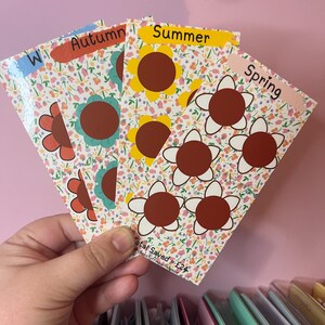 Może przedstawiać: Cztery kolorowe karty z kwiatowym wzorem i motywem słonecznika. Każda karta ma napisane na niej inną porę roku: zima, jesień, lato i wiosna. Karty mają w sumie 12 brązowych środków słoneczników. Tekst "Total Saved = £24" znajduje się na dole kart.