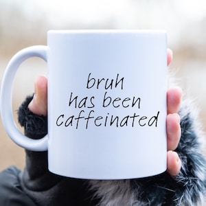 May include: White ceramic mug with a black handwritten message that reads "bruh has been caffeinated".