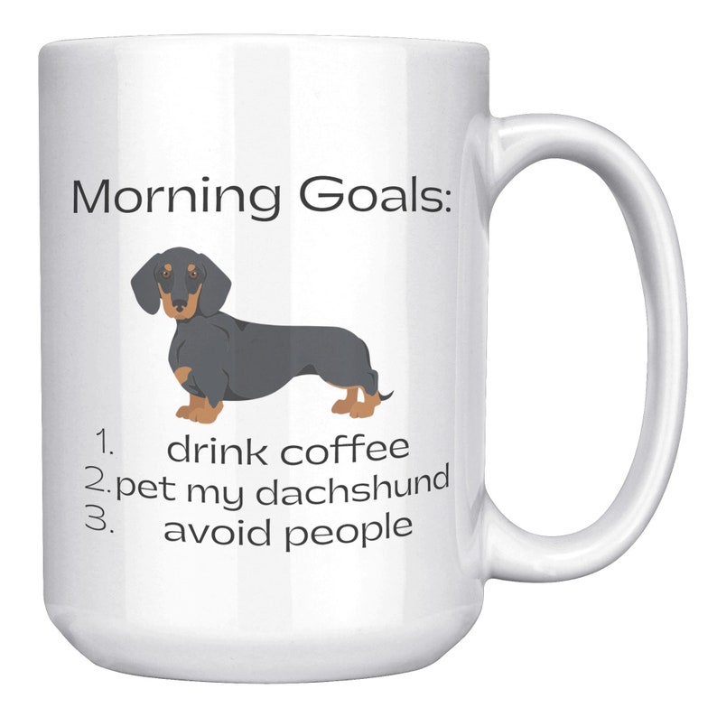 May include: White coffee mug with a black and tan dachshund illustration and the text "Morning Goals:" 1. drink coffee 2. pet my dachshund 3. avoid people