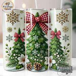 May include: A set of three Christmas-themed tumblers. Each tumbler features a green Christmas tree design with red plaid bows, snowflakes, and white flowers. Gold snowflakes and the text "10 Free Designs Included" are also visible.