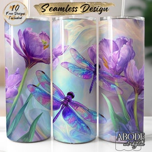 May include: A set of three 20 oz. stainless steel tumblers featuring a seamless design of purple dragonflies and tulips. The tumblers have a light blue and purple background with the text "Seamless Design" and "10 Free Designs Included".