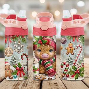 May include: Three views of a cylindrical water bottle with a pink lid and straw. The bottle features a festive Christmas design with a fluffy highland cow wearing a red hat and scarf, gingerbread cookies, candy canes, snowflakes, and holly.