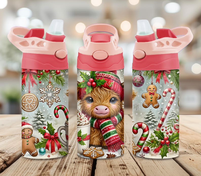 May include: Three views of a cylindrical water bottle with a pink lid and straw. The bottle features a festive Christmas design with a fluffy highland cow wearing a red hat and scarf, gingerbread cookies, candy canes, snowflakes, and holly.
